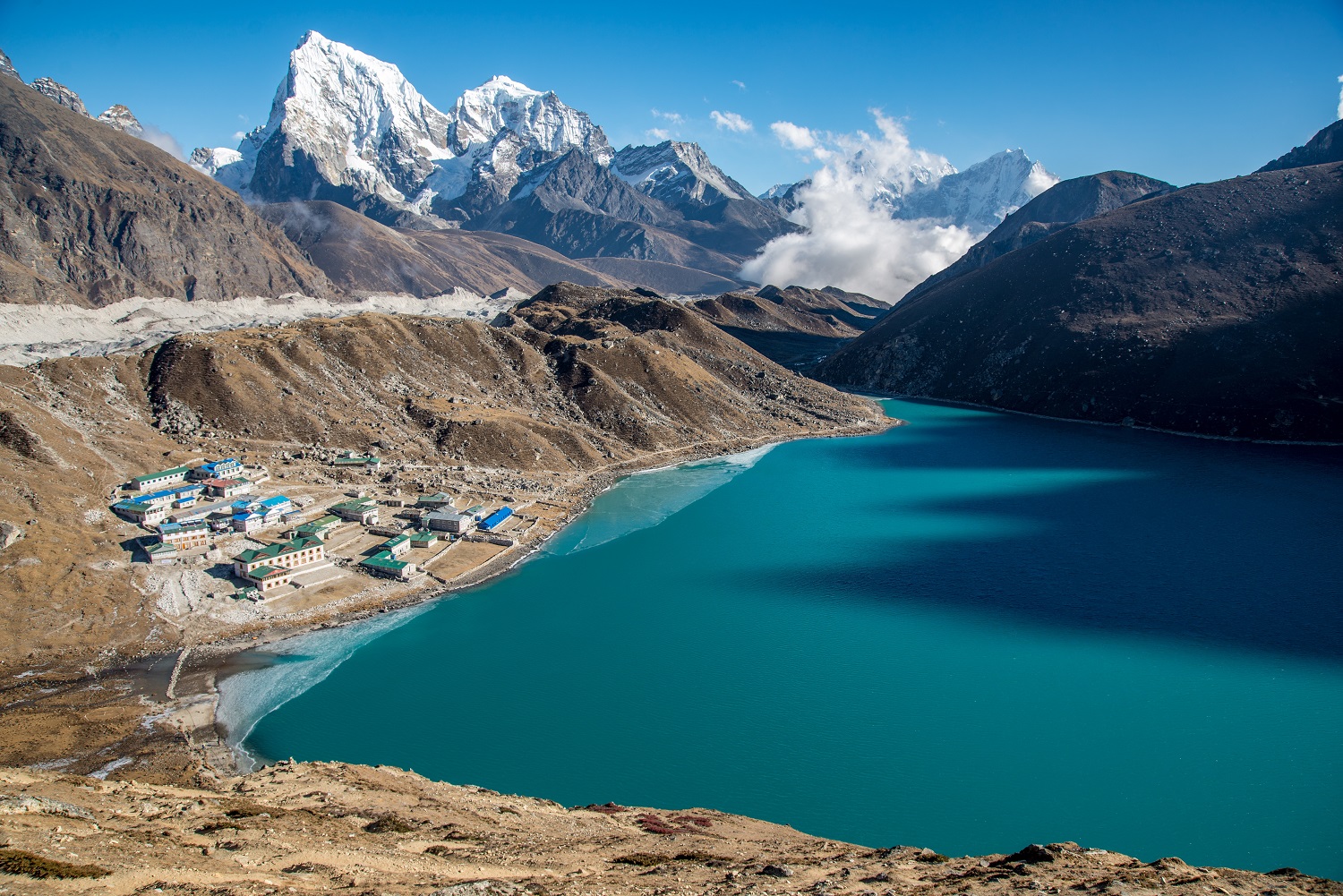 A high shot of a small town near a blue body of water surrounded by beautiful mountains.